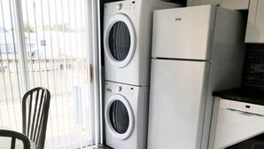 Eine Küche mit integriertem Wasch- und Trockner, einem Essbereich mit Tisch und Stühlen sowie einem Ausblick durch ein Fenster.