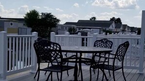 Eine Terrasse mit Tisch und Stühlen, umgeben von einem weißen Zaun, mit Blick auf eine Wohngegend.