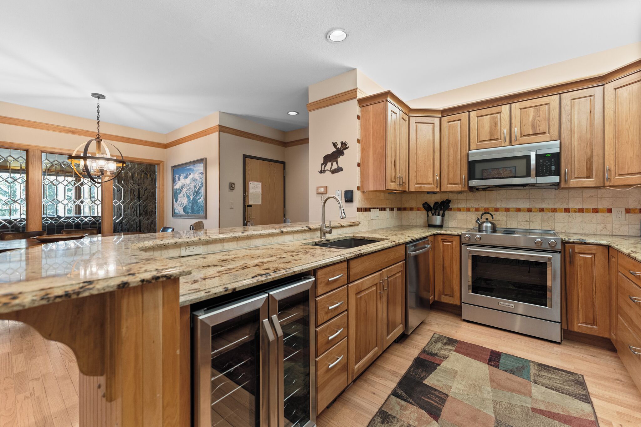A modern kitchen with wooden cabinets, stainless steel appliances, and a granite countertop.