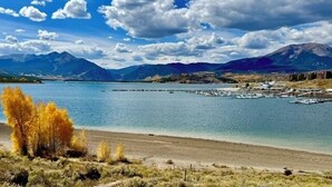 A lake with mountains in the background, a dock with boats, and a clear sky.