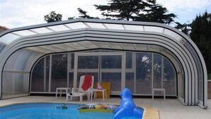 A covered swimming pool with a glass enclosure, a blue inflatable toy, and a red towel on a chair. - APARTMENT T3 in villa 4 faces in BANYULS on sea PARKING CLOS (Banyuls-sur-Mer)