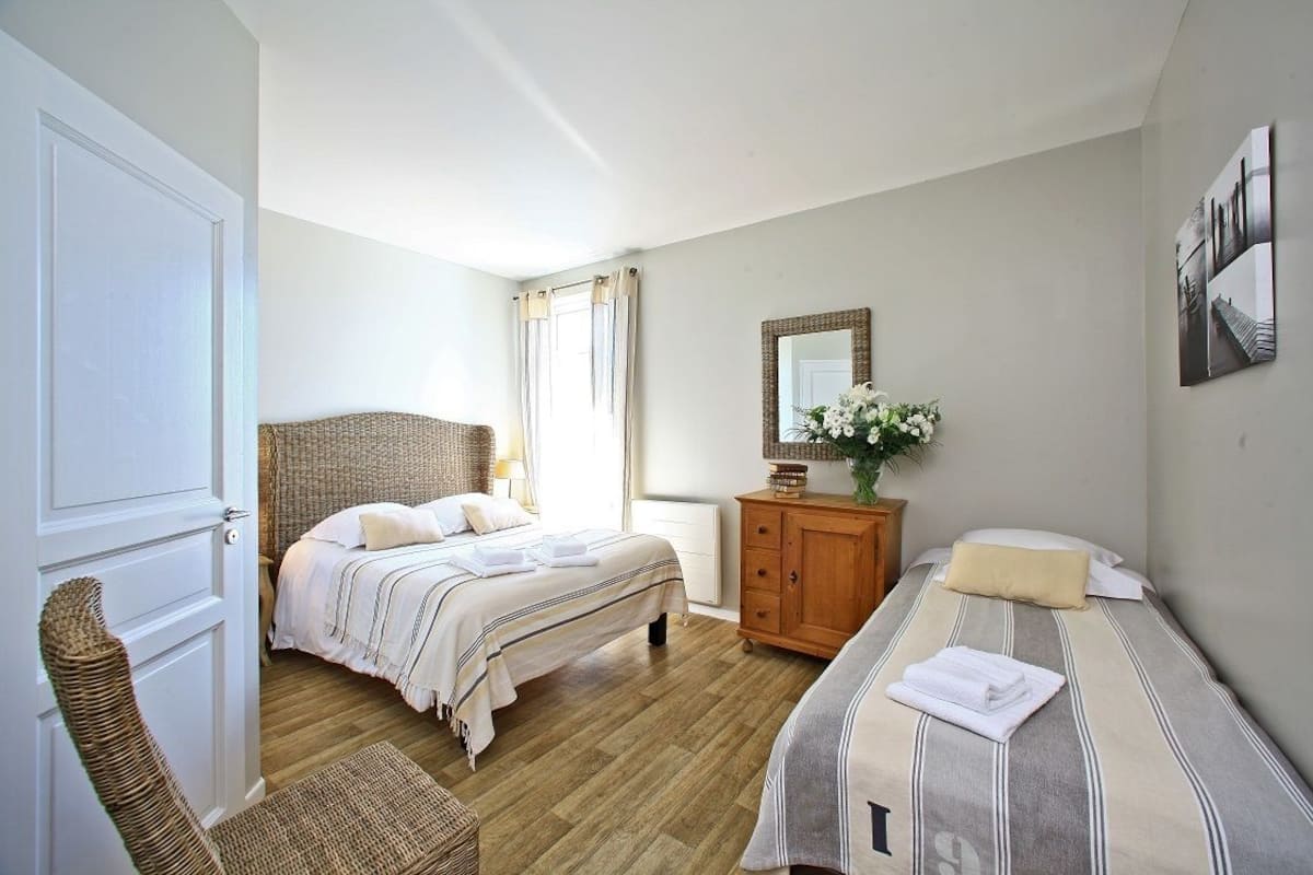 Ein Schlafzimmer mit Bett, Stuhl, Kommode und Spiegel.