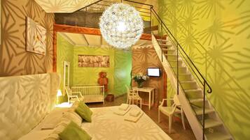 Une chambre à coucher avec un grand lit, un berceau, un ours en peluche, un bureau avec un ordinateur et un escalier.