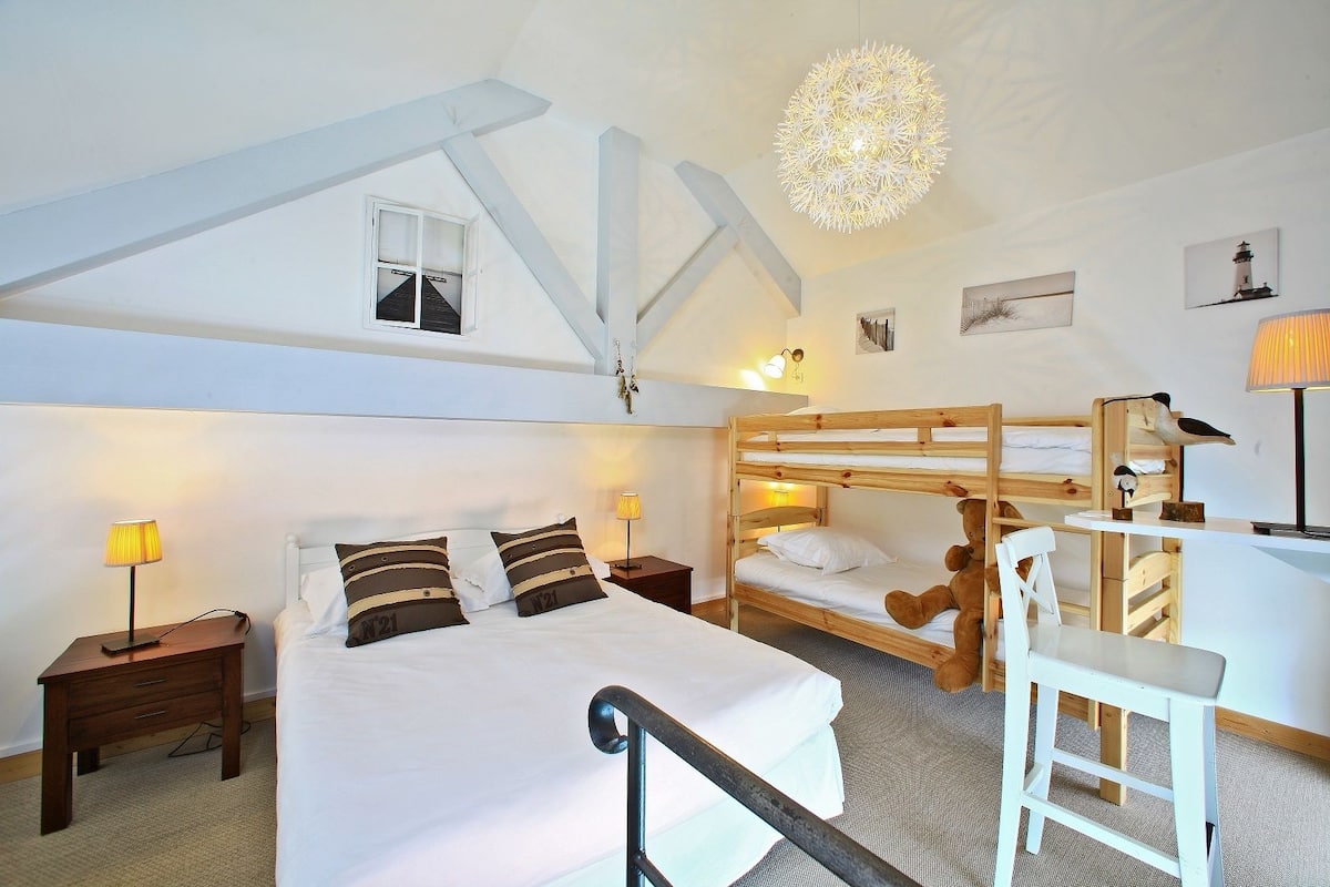 Ein Schlafzimmer mit Etagenbett, Schreibtisch, Stuhl, Nachttischlampen und einer Deckenleuchte.