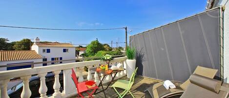 A balcony with a table, chairs, and a potted plant.