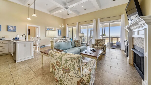 A spacious living area with a ceiling fan, a fireplace, and a balcony with a view. - JonBie Maison Ocean Serenity Cottage  Oceanfront Cart included with Booking. (Daufuskie Island)