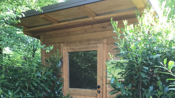 Une structure en bois dotée d’une porte et d’un petit porche.