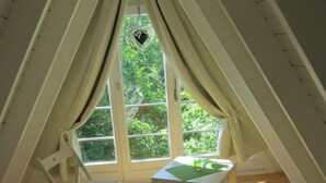 Une chambre confortable située sous les combles, avec une grande fenêtre, une petite table et une chaise.