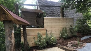 Une clôture en bois, une zone recouverte de gravier et une structure en bois dotée d’un toit incliné.