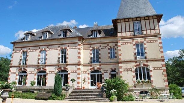 A large, historic building with a prominent tower, multiple windows, and a well-maintained garden with outdoor seating. - Chateau 150kms south of Paris for 15 people (Cerdon)
