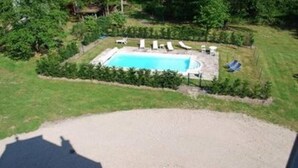 An aerial view of a backyard with a swimming pool, surrounded by a hedge, and a circular patio area. - Chateau 150kms south of Paris for 15 people (Cerdon)
