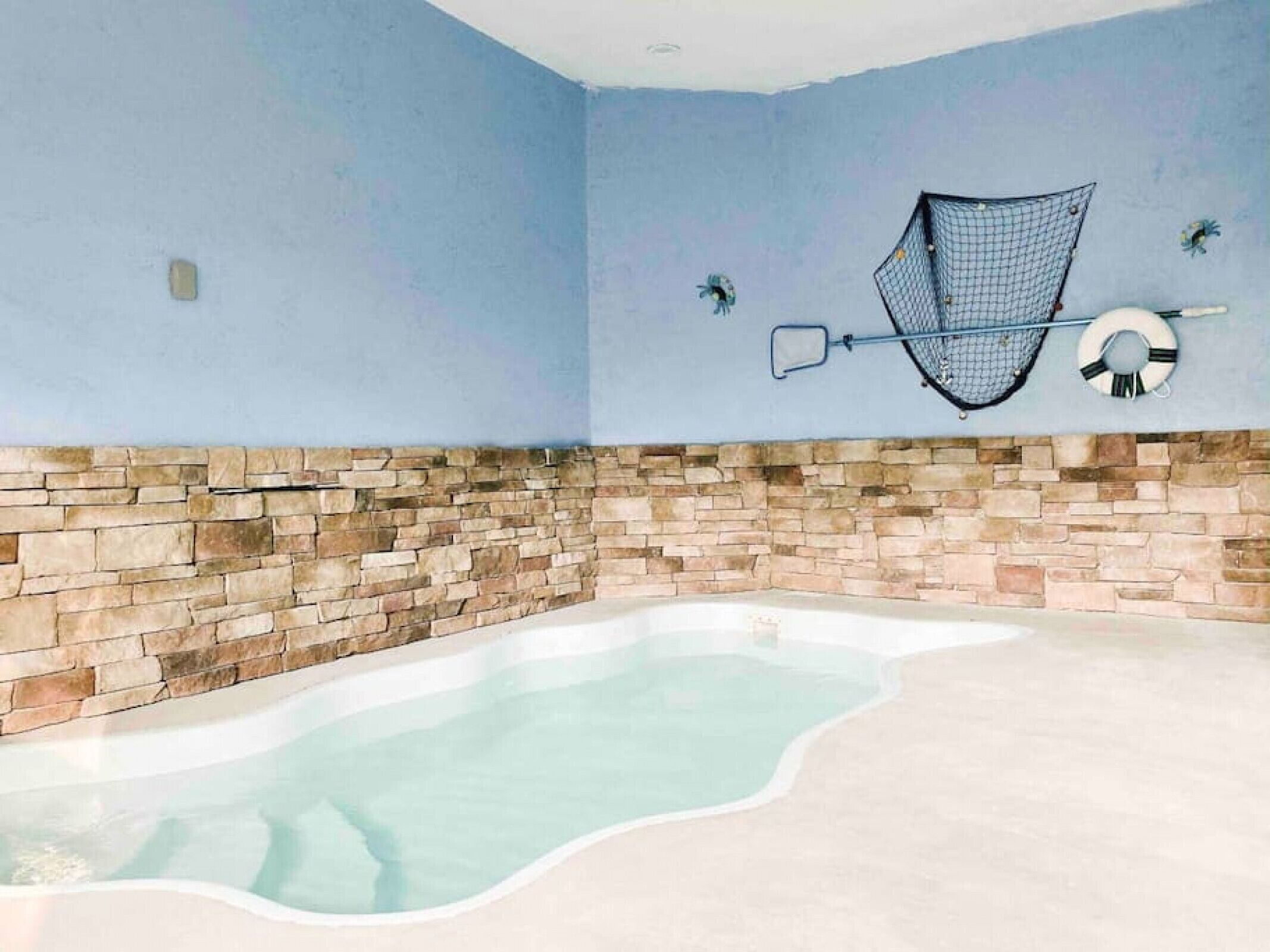 A swimming pool with a stone wall and a blue ceiling.