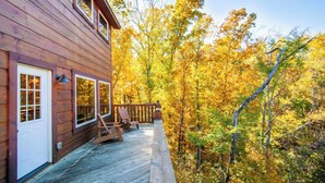 Eine Holzhütte mit einer Terrasse, umgeben von Herbstlaub.