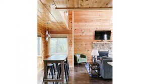 Ein Holzinterieur mit Esstisch, Stühlen, einer Couch und einem Kamin.