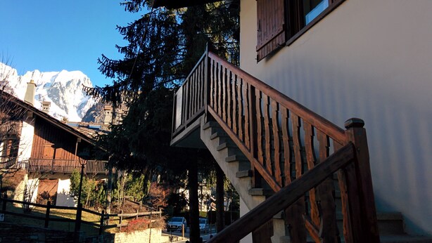 A staircase leading to a balcony with a mountain view in the background. - large and comfortable apartment in Courmayeur (Courmayeur)