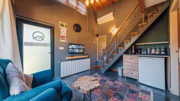 A modern living room with a blue sofa, a coffee table, and a staircase leading to a kitchen area.