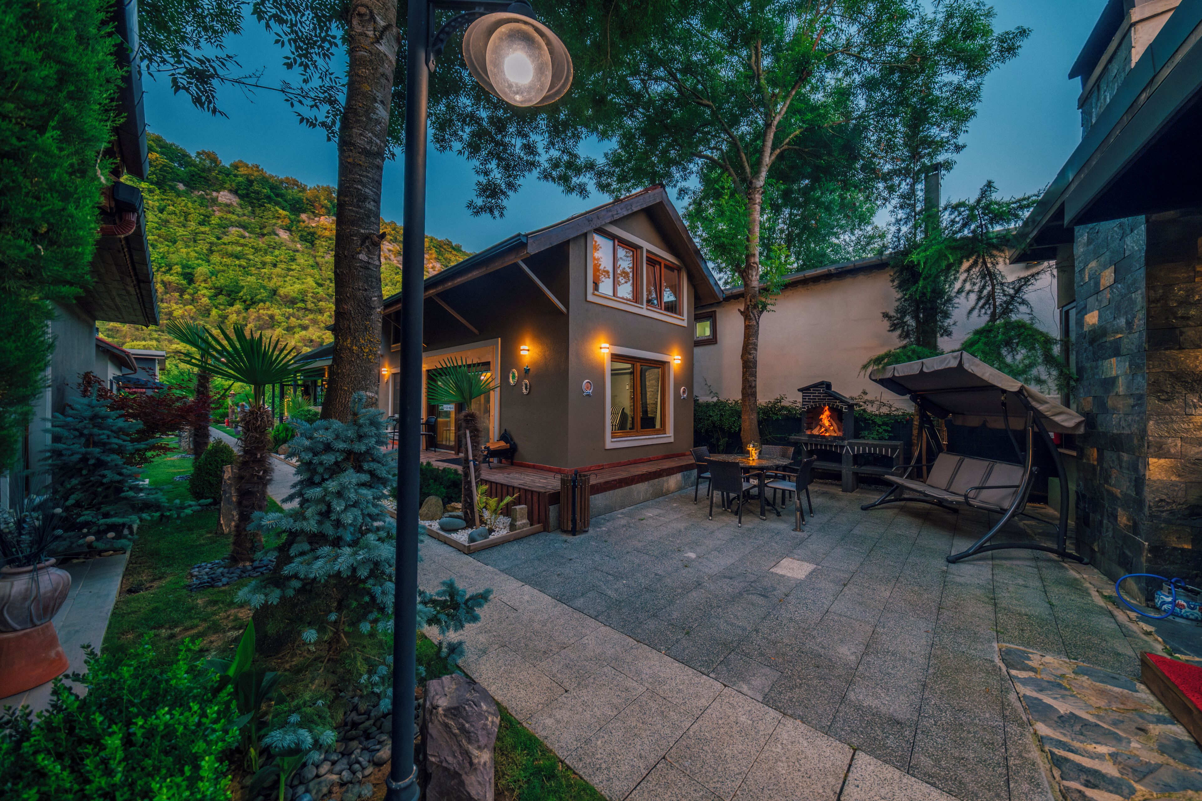 A cozy outdoor patio area with a stone floor, a fire pit, and a seating area with a table and chairs.