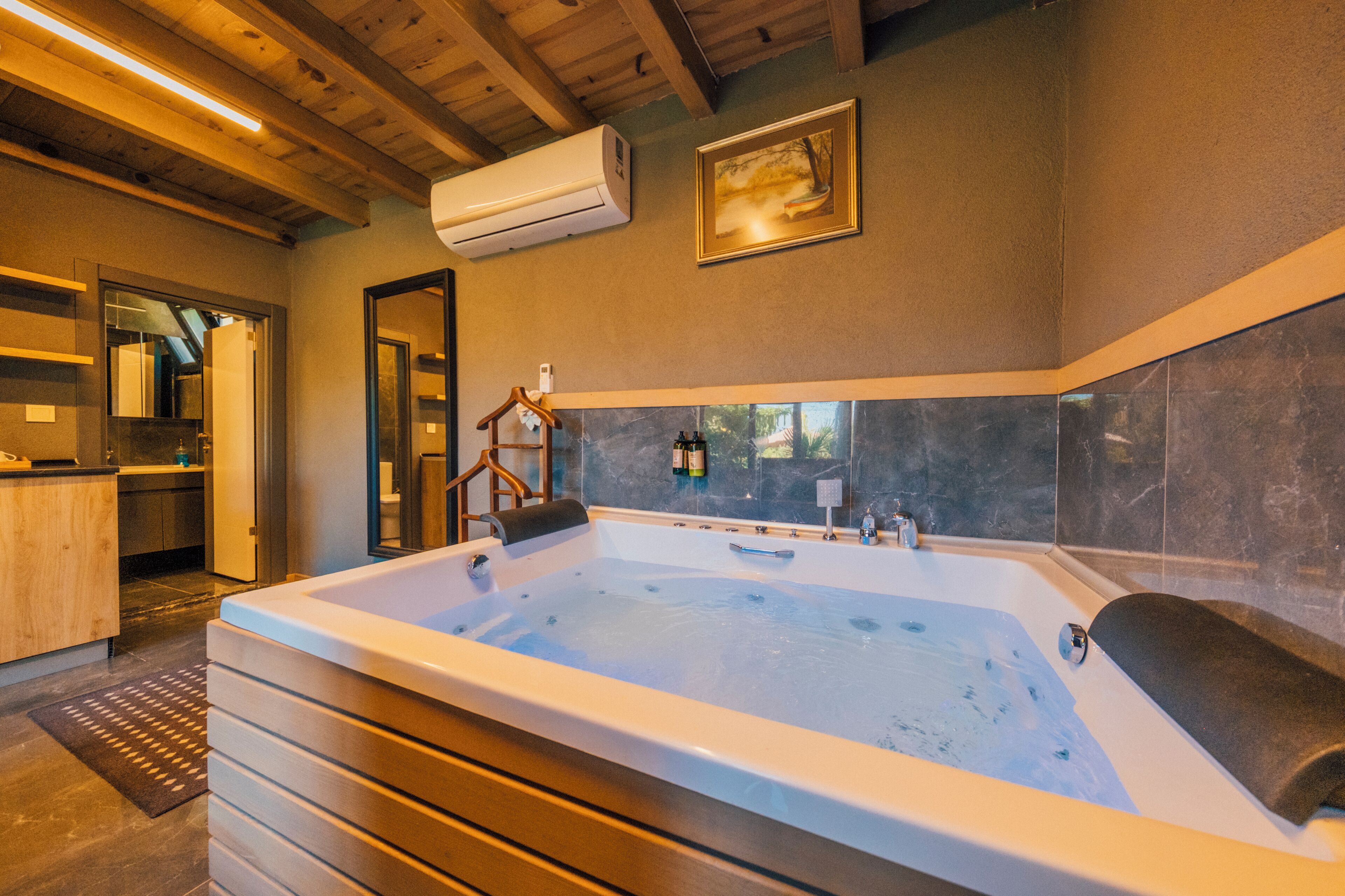 Une salle de bain moderne avec une grande baignoire, un plancher en bois et une vue sur l’extérieur.