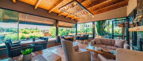 Un restaurante moderno con techos de madera, ventanas amplias y una variedad de opciones de asientos, incluidas mesas y sofás.