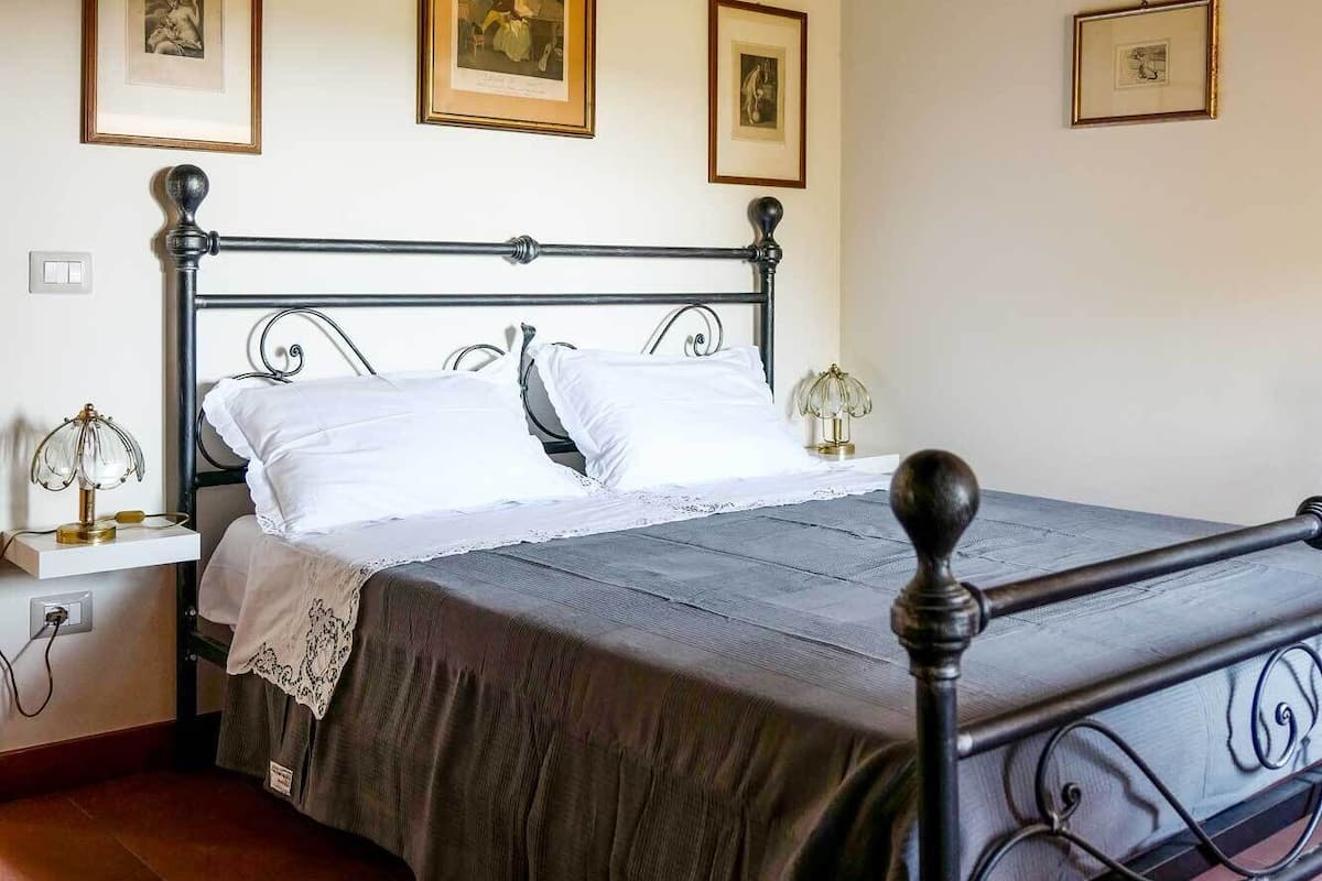 A bedroom with a bed, a nightstand, and a wall-mounted shelf.