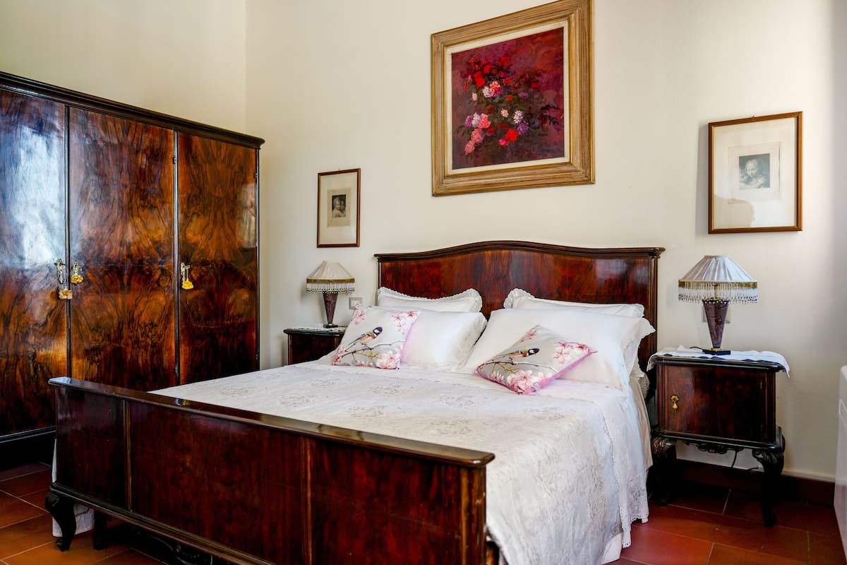 A bedroom with a wooden bed, a wardrobe, and two bedside tables with lamps.
