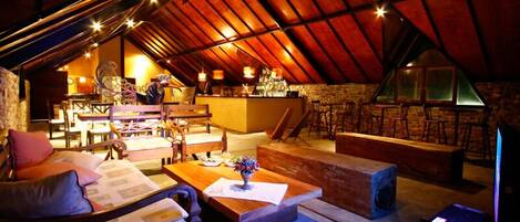 An attic-style living room with a dining area, wooden furniture, and a stone wall.