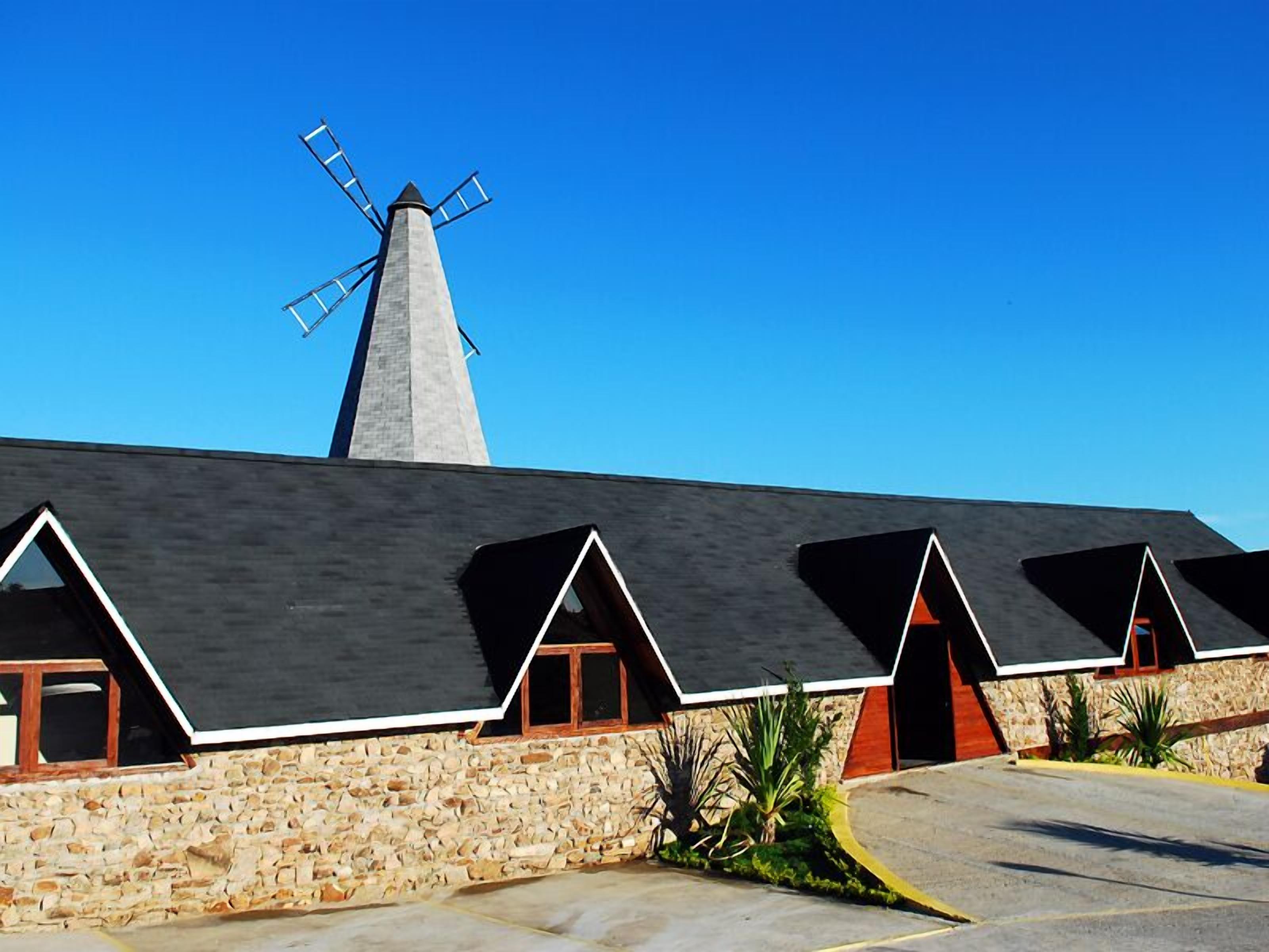Un edificio con un molino, muros de piedra y varias habitaciones con techos inclinados.