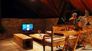 A cozy, rustic room with a stone wall, wooden furniture, and a television.
