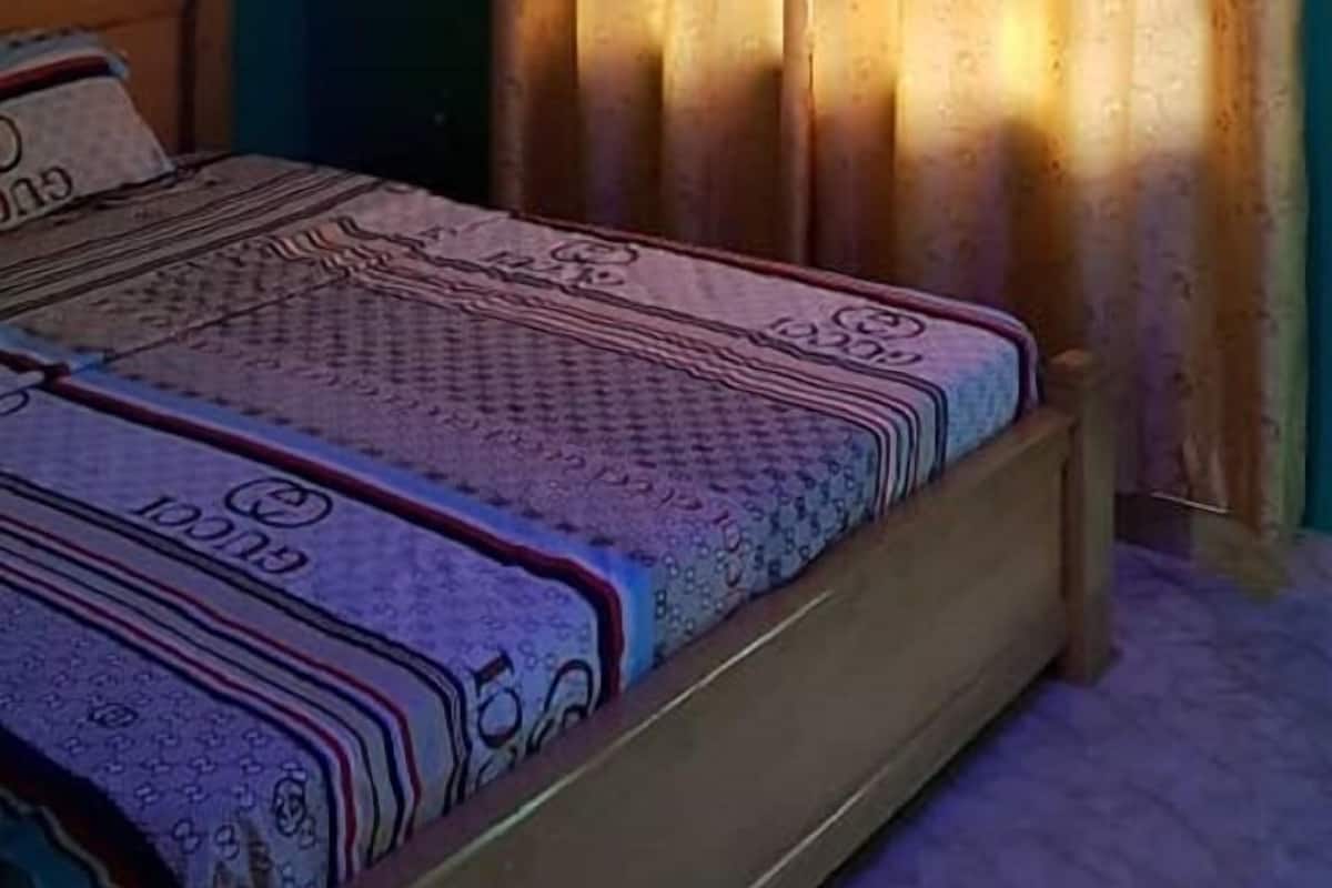 A bedroom with a bed, a ceiling fan, and curtains.