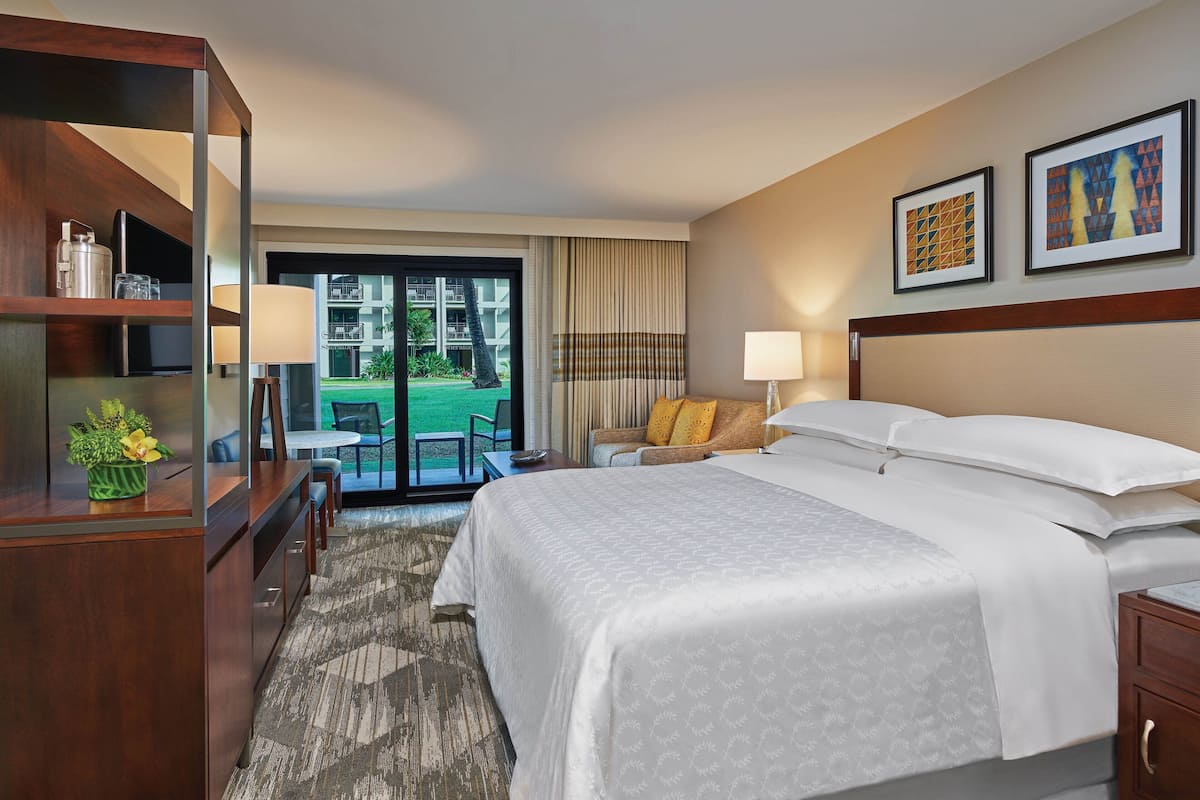 Habitación de hotel con una cama grande, un escritorio con lámpara, una silla y vistas al exterior.