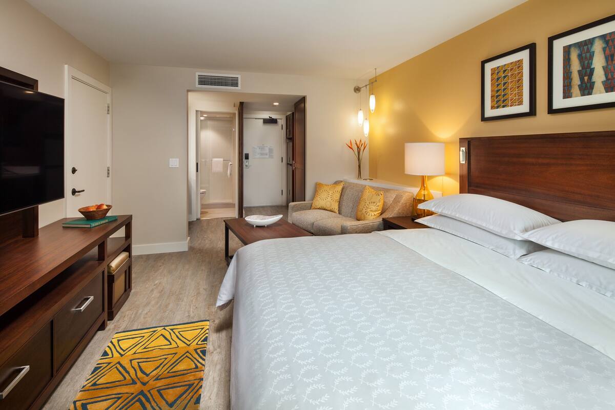 Una habitación de hotel con cama, televisión, escritorio y sofá.