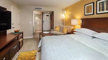 A hotel room with a bed, a TV, a desk, and a sofa.