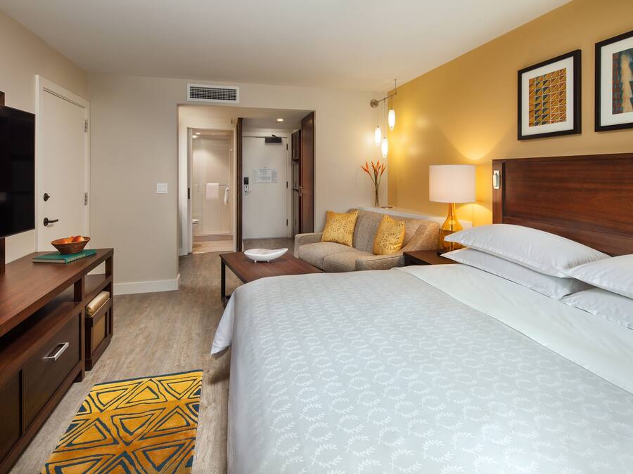 A hotel room with a bed, a TV, a desk, and a sofa.