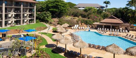 A resort with a swimming pool, sun loungers, and thatched umbrellas.