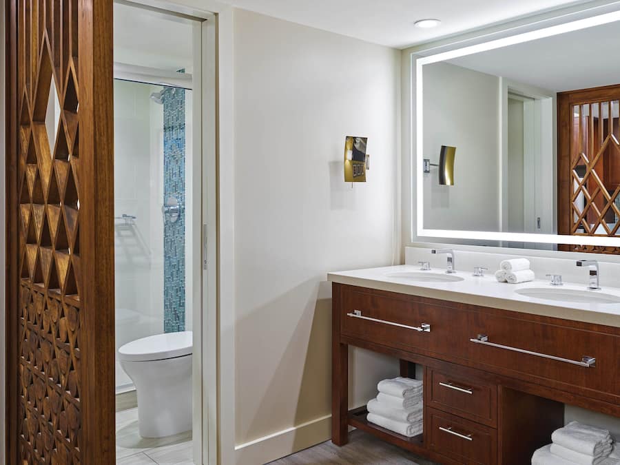 A modern bathroom with a wooden vanity, two sinks, and a large mirror.