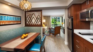 Una cocina moderna con armarios de madera, un refrigerador de acero inoxidable y una zona de comedor con una mesa de madera y sillas azules.