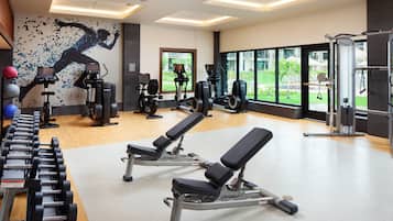 Un gimnasio con equipo de ejercicio variado, incluyendo cintas de correr, elípticas y pesas libres.