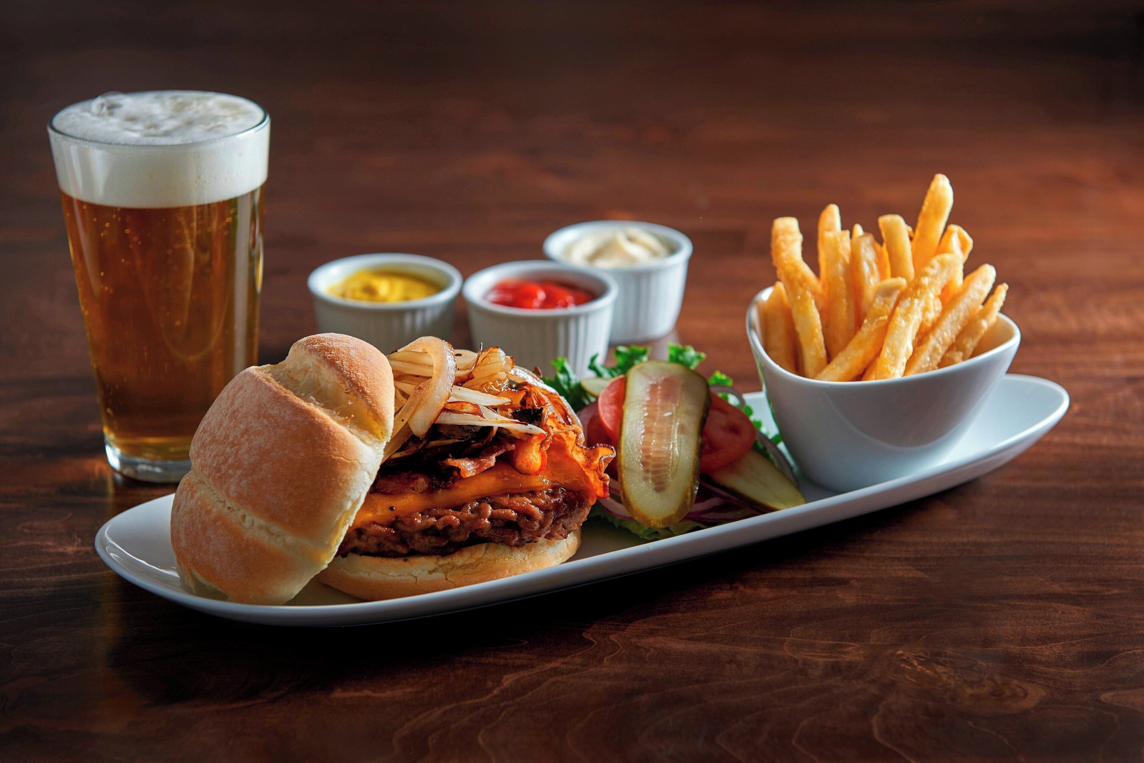 Un plato con una hamburguesa, papas fritas y una cerveza.