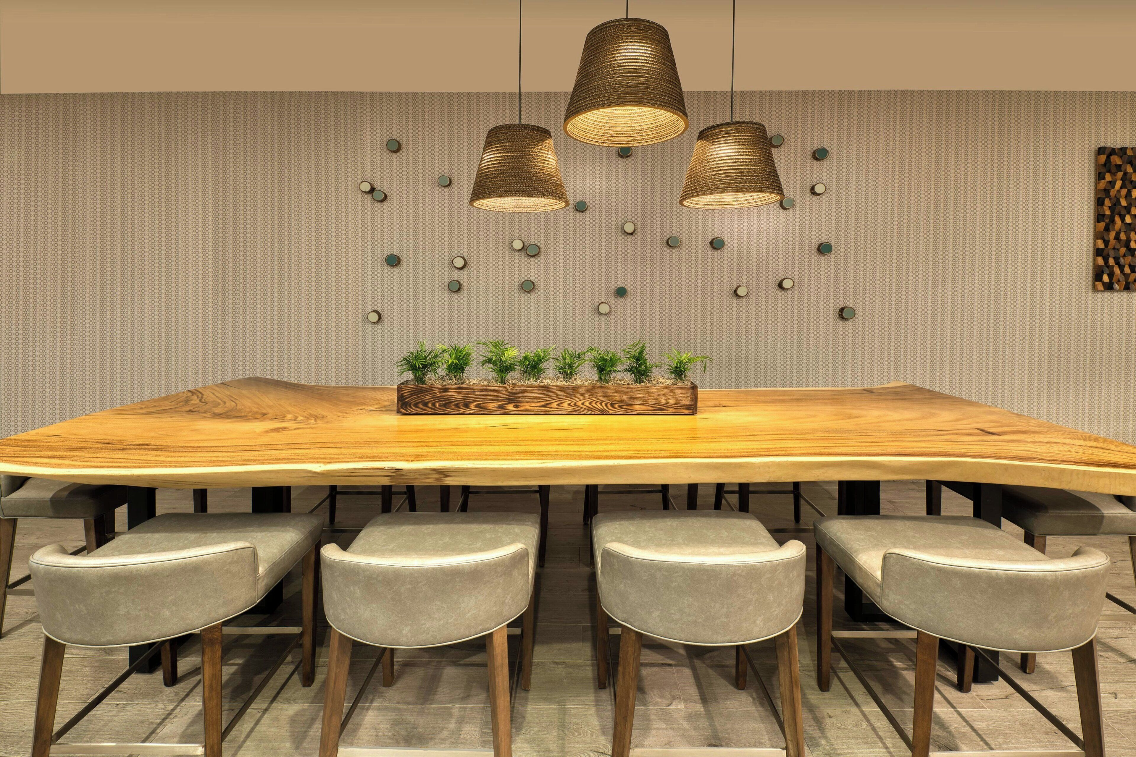 A conference table with four chairs, three pendant lights, and a decorative wall with circular elements.