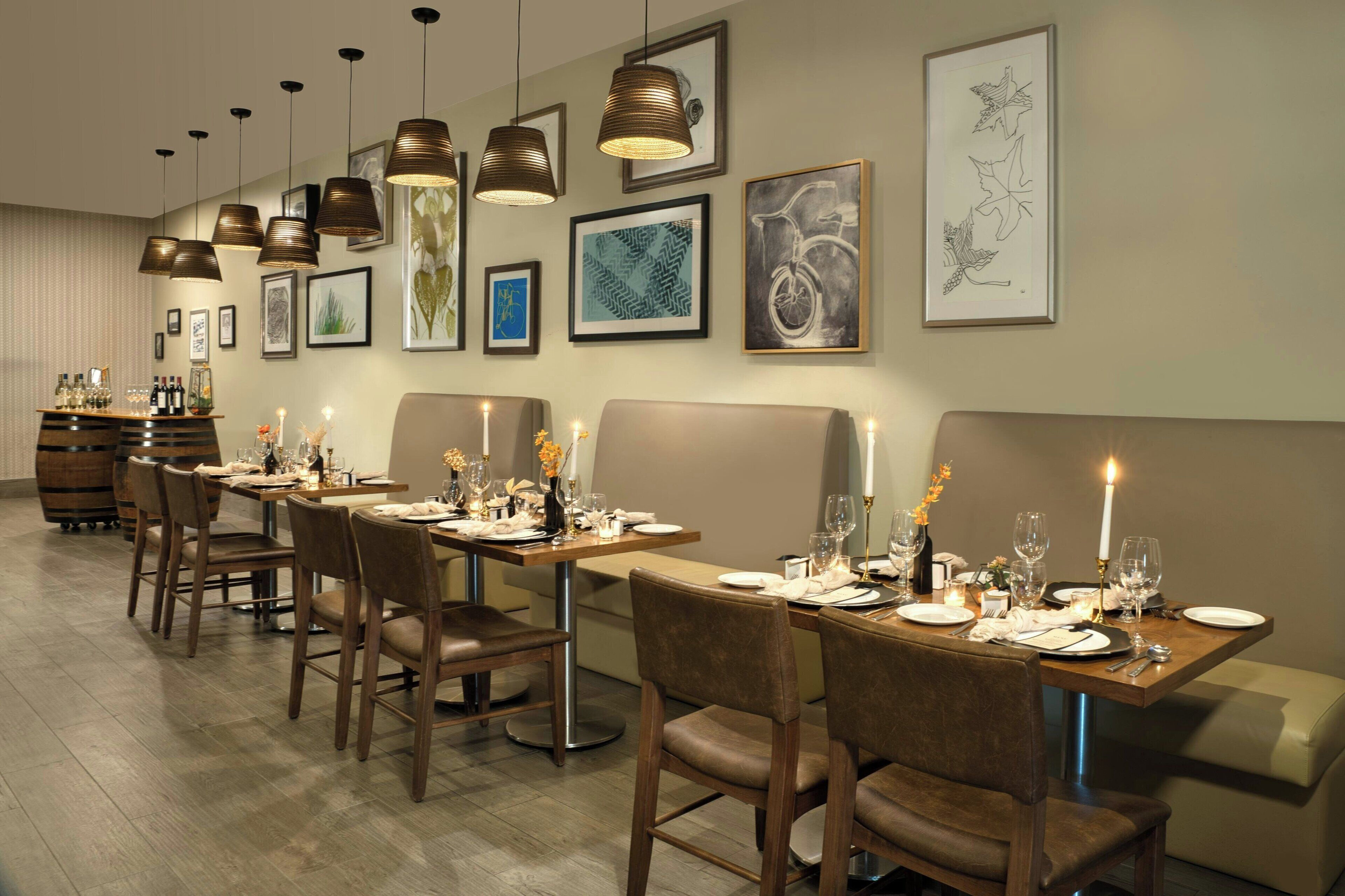 A dining area with multiple tables set for a meal, featuring a variety of framed artworks on the walls.
