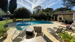 A backyard with a swimming pool, outdoor furniture, and a barbecue area.