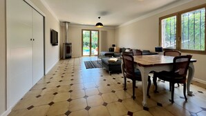 A spacious living area with a dining table, chairs, a sofa, and a large window providing a view of the outdoors.