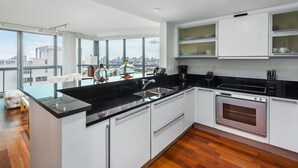 Una cucina moderna con piano di lavoro nero, elettrodomestici in acciaio inossidabile e mobili bianchi.
