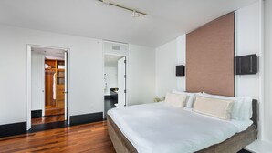 Una moderna camera d'hotel con un letto grande, un cabina armadio e una TV a schermo piatto montata a parete.