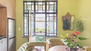 Un área de comedor con una mesa, sillas, un sofá y una ventana con vidrieras.