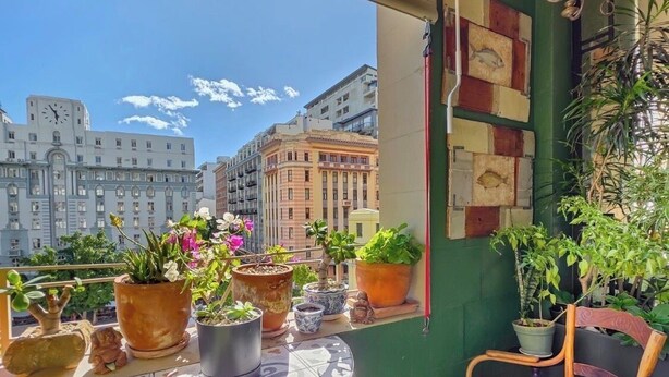 Un balcón con plantas en macetas, una mesa redonda y una silla.
