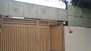A large wooden gate with a sign reading "H#55" on a beige wall. - Amyls garden (Islamabad)