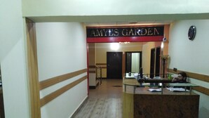 A reception area with a reception desk, a sign reading "AMY'S GARDEN," and a person sitting at the desk. - Amyls garden (Islamabad)