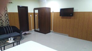 A room with a sofa, a small table, a television mounted on the wall, and a wooden wardrobe. - Amyls garden (Islamabad)