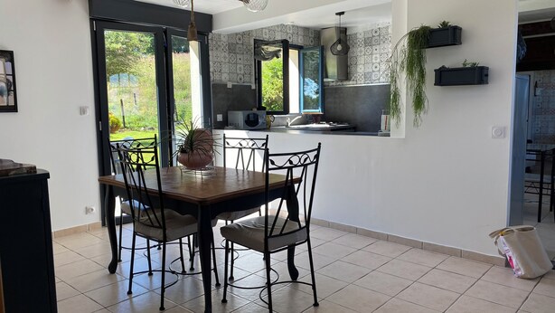 Una cocina moderna con comedor, ventanas amplias y vistas al verdor.